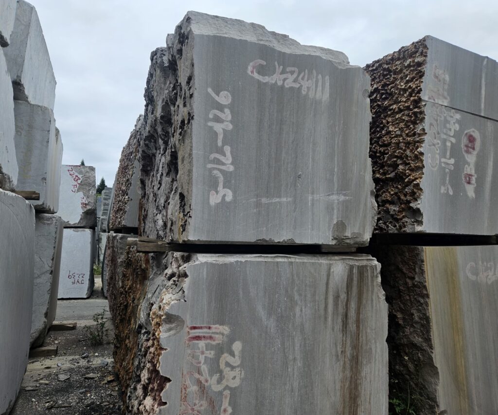 Two blocks of this stone stacked on each other in the yard, each sawn face showing the straight lines of the bed running down it and the yellow-brown iron staining along the edges.