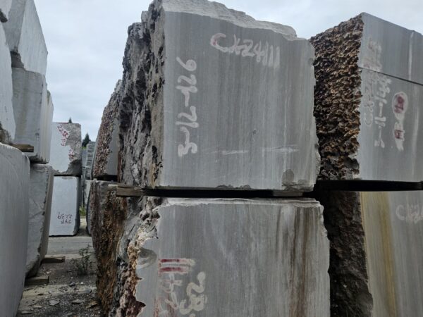 Two blocks of this stone stacked on each other in the yard, each sawn face showing the straight lines of the bed running down it and the yellow-brown iron staining along the edges.