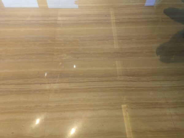 The floor of a shopping centre concourse laid in this stone, the boards running with the walkway and the polished face holding the reflection of the ceiling lights.