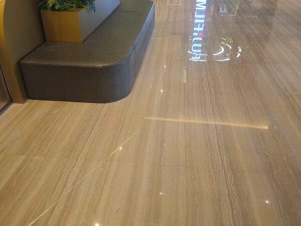 The floor of a shopping centre concourse laid in this stone, with a bench and a planter at the edge of it and the boards running with the walkway.