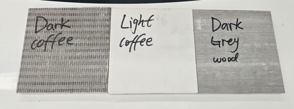 Three stone sample boards laid side by side on a white surface, labelled in marker pen dark coffee, light coffee and dark grey wood